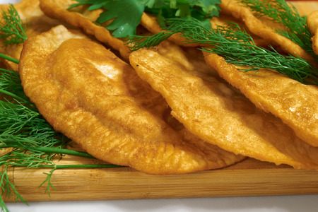 pastries of thin unleavened dough stuffed with meat and hot spices on a wooden deck with dillの写真素材