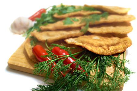 pastries of thin unleavened dough stuffed with meat and hot spices on a wooden deck with dill and pepperの写真素材