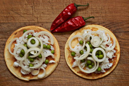 pancakes with rice and green peas, red pepper lie on a wooden board