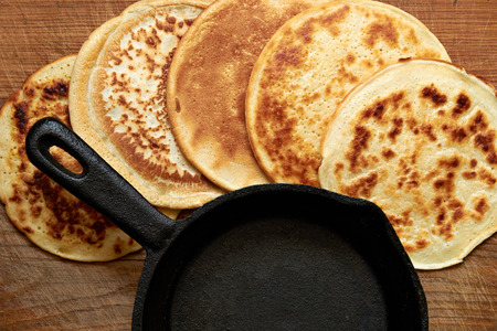 four round pancakes and cast iron skillet on a wooden tableの写真素材