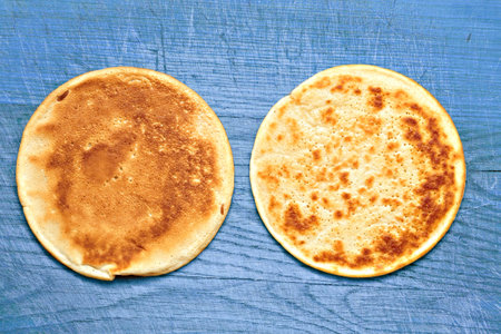 two yellow pancakes on a old wooden board