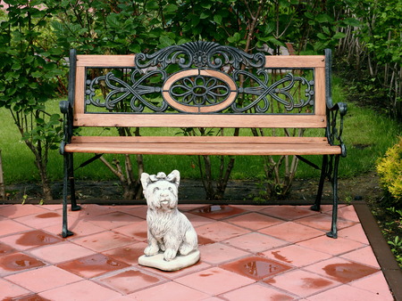 A bench and a sculpture of a small dog in the Park.の写真素材