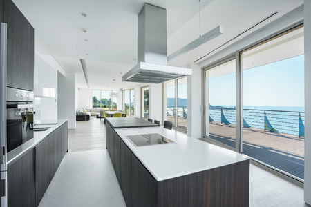 Interior of light spacious kitchen with large panoramic windows in a luxury villaの写真素材