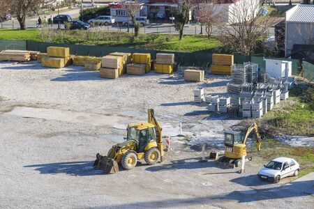 Budva, Montenegro, December 02, 2019: Construction work on the construction site of the city. Excavator digs a pit, a worker is directing the workのeditorial素材