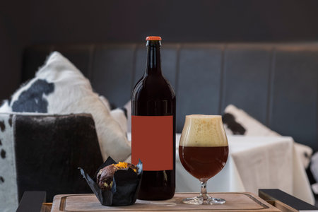 Bottle of cherry ale, full beer glass with froth, chocolate muffin on wooden trayの写真素材