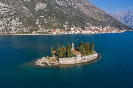 Aerial shot, drone flies above the blue sea to the small Island. On one island there is a Christian...
