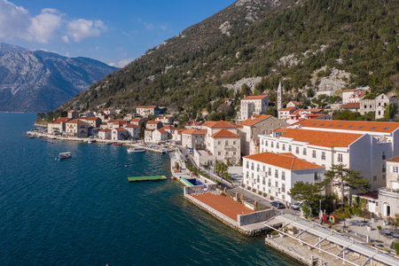 Aerial shot of the old coastal town of Perast at the foot of the mountain. Seaside promenade,...