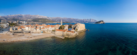 Aerial View of Budva Old Town and sandy beach in a beautiful spring day. Top view from drone on the...