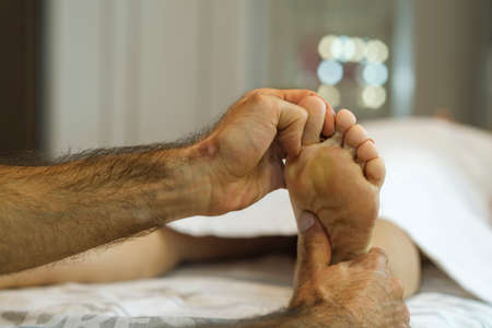 In a beauty salon, a professional massage therapist gives the woman client a therapeutic and relaxing foot massageの写真素材