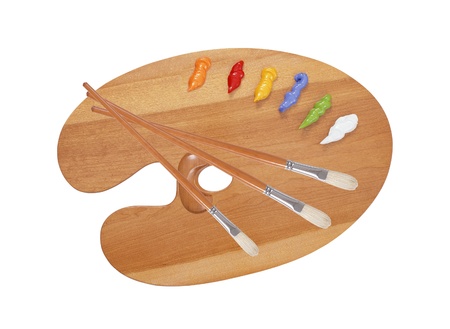 wooden art palette with blobs of paint and a brush on white background の写真素材