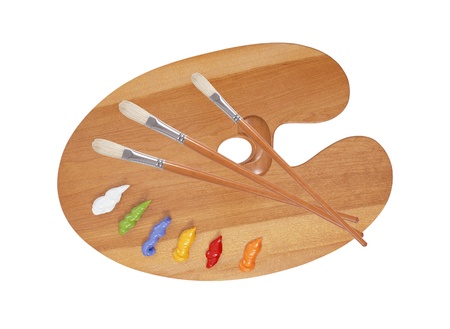 wooden art palette with blobs of paint and a brush on white background の写真素材