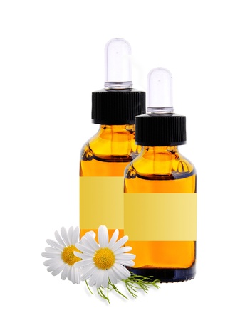 bottles with essence oil and chamomiles isolated on whiteの写真素材