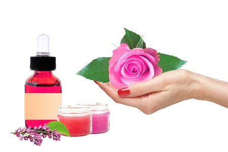 Pink rose in woman hand and bottle with essence oil on white backgroundの写真素材