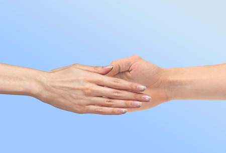 Women's hand goes to the man's hand on blue backgroundの写真素材