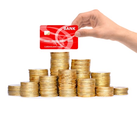 Many coins in column and hand with credit card isolated on whiteの写真素材