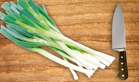 green onion and knife on cutting board isolated on whiteの写真素材