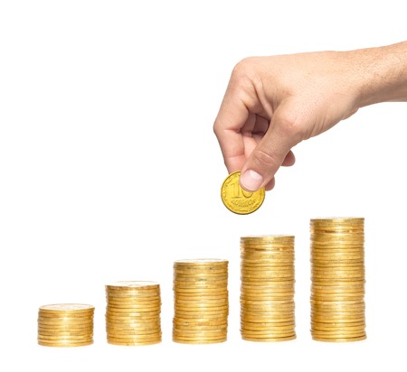 Savings, increasing columns of gold coins and man hand isolated on white backgroundの写真素材