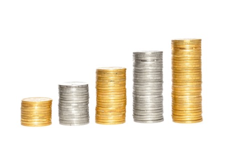 Savings, increasing columns of gold and silvercoins over white backgroundの写真素材