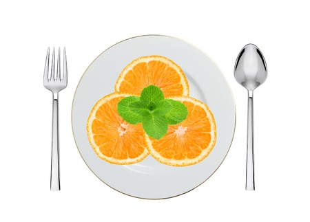 juicy orange on white plate, spoon and fork isolated on whiteの写真素材