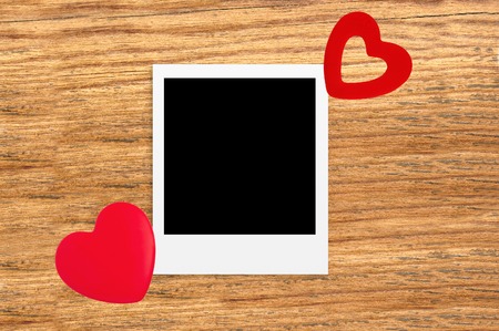 Two red heart shaped valentine's / christmas red decorations on rustic wooden background with photo frameの写真素材