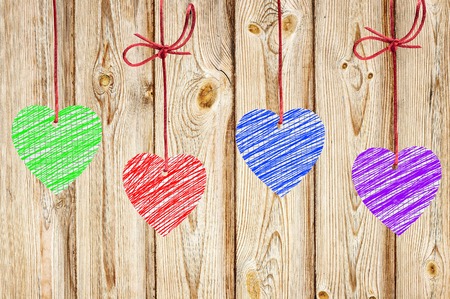 painted hearts hanging on the wooden weathered rustic backgroundの写真素材