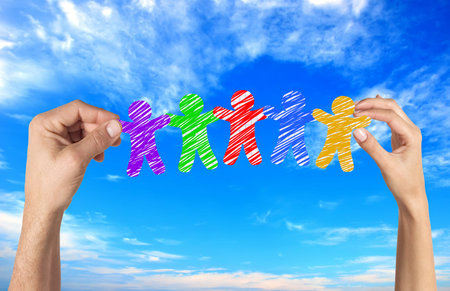 Paper people in woman and man hands over blue skyの写真素材