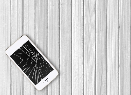 Modern broken mobile phone on white wooden backgroundの写真素材