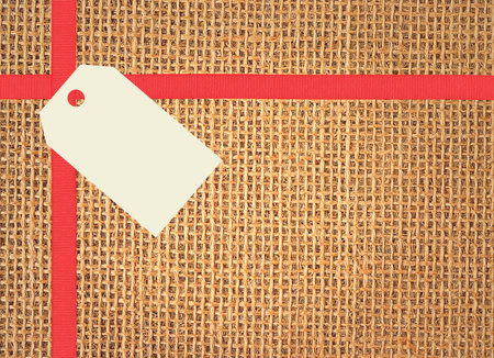 Linen texture background with red ribbon and tag