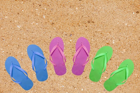 colorful beach shoes on yellow sand backgroundの写真素材