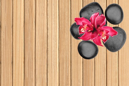 Black spa stones and pink orchid flower on wooden backgroundの写真素材