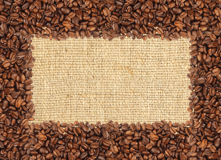 Spilled coffee beans frame over burlap textileの写真素材