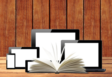 Tablet pc, mobile phone, computer and openned book on wooden table
