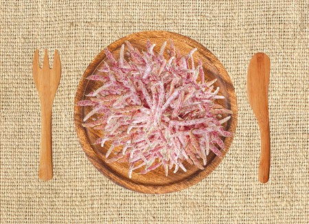 Color beans on wooden plate, fork and knife on the llinen texture backgroundの写真素材