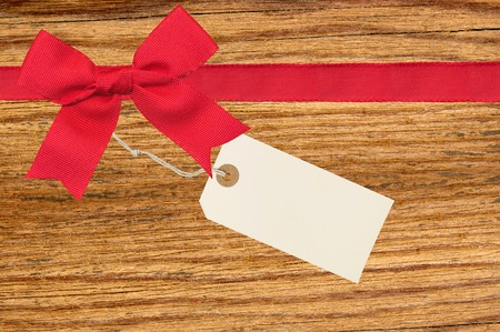 Red ribbon with a tag on wooden backgroundの写真素材