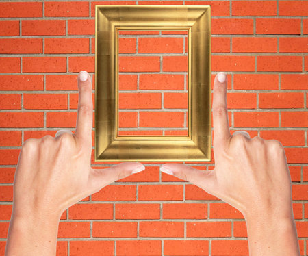 Finger frame and wooden frame over orange brick wall