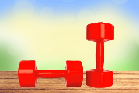 Red dumbbells fitness on wooden table over nature backgroundの写真素材