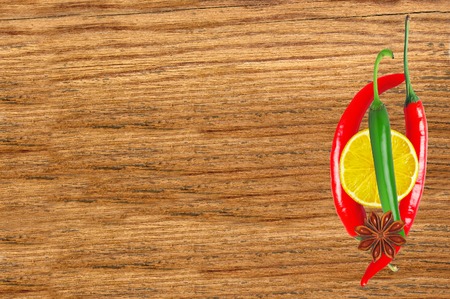 Hot peppers and lemon slice on wooden table close upの写真素材