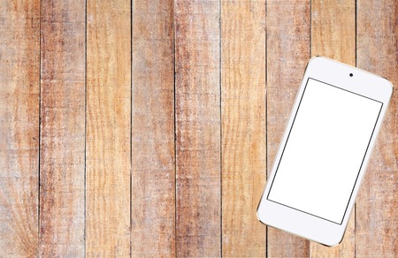 White Mobile Phone on Brown Old Wood Plank Texture Backgroundの写真素材