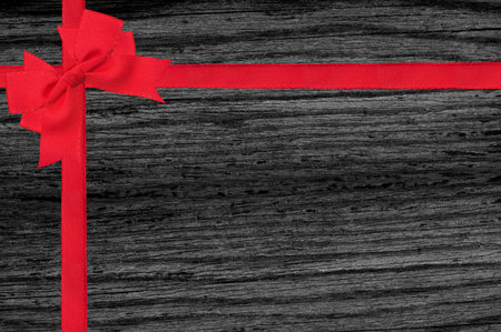 Black wood texture with red ribbon and bow close-up backgroundの写真素材