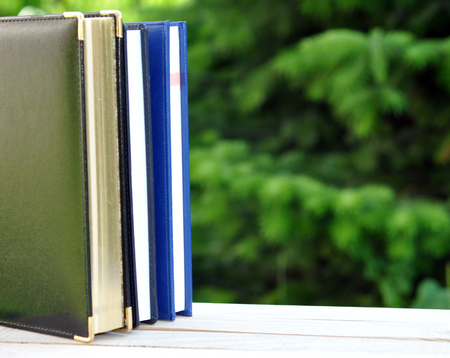 closed books with golden pages on wooden table outdoor over summer garden nature backgroundの写真素材