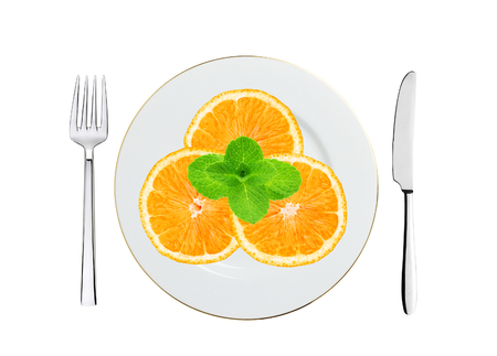 juicy orange on white plate, knife and fork isolated on whiteの写真素材