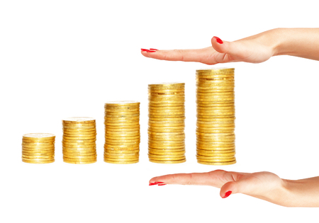 columns of gold coins and woman hands isolated on white backgroundの写真素材