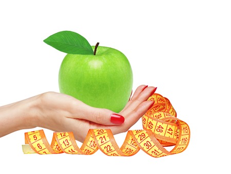 Big green apple in woman hand and measure tape isolated on white backgroundの写真素材