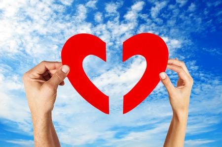 hands holding two half of heart shape with blue sky backgroundの写真素材