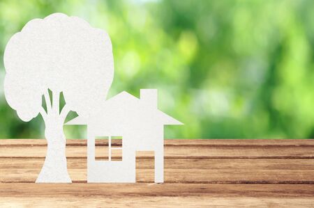 Paper house and tree on wooden table with garden bokeh outdoor themeの写真素材