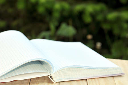 book with open empty white pages on the table over green nature background outdoorの写真素材