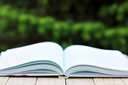 book with open empty white pages on the table over green nature background outdoorの写真素材