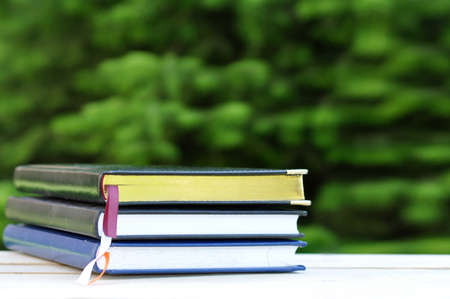 closed books with golden pages on wooden table outdoor over summer garden nature backgroundの写真素材