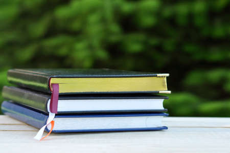 closed books with golden pages on wooden table outdoor over summer garden nature backgroundの写真素材