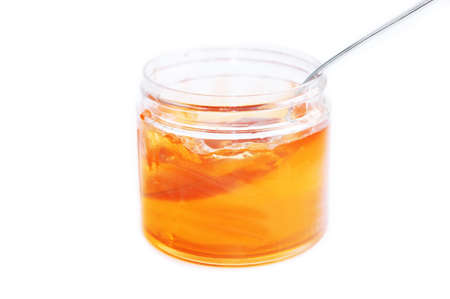 sweet yellow honey food in glass jar with spoon isolated on white backgroundの写真素材